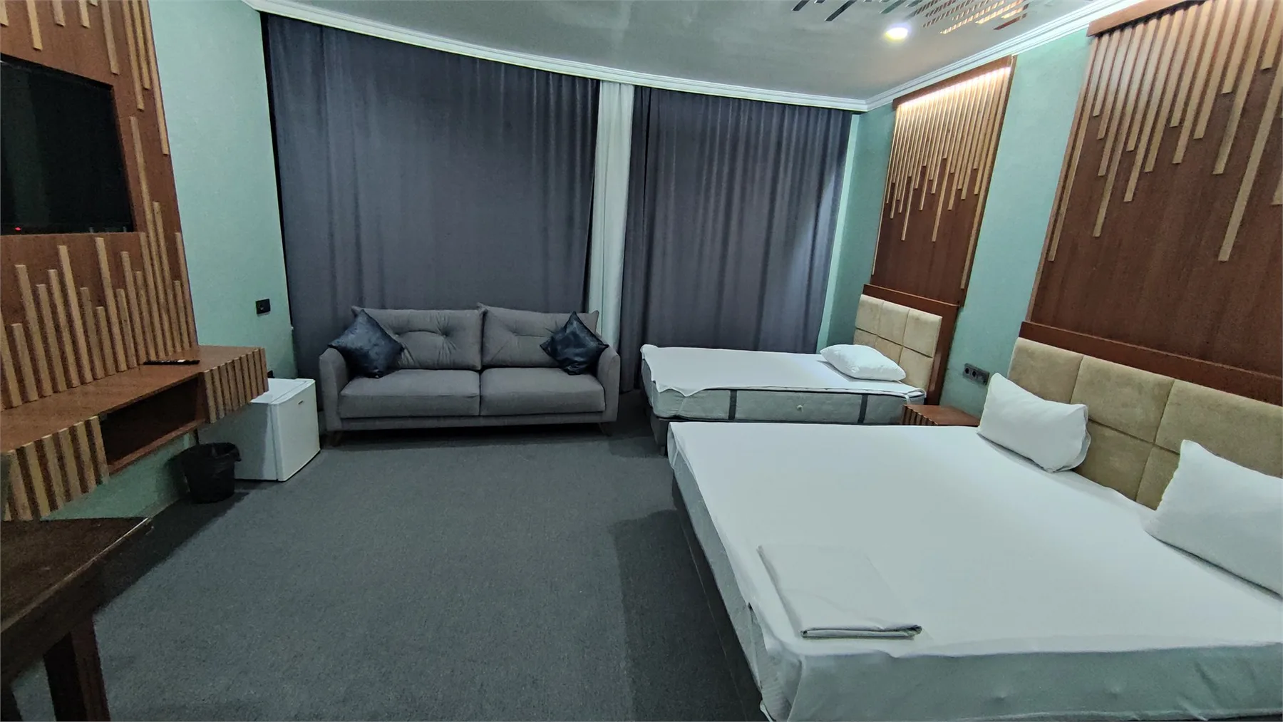Representative hotel space: A hotel room with two beds, a sofa, and dark curtains.