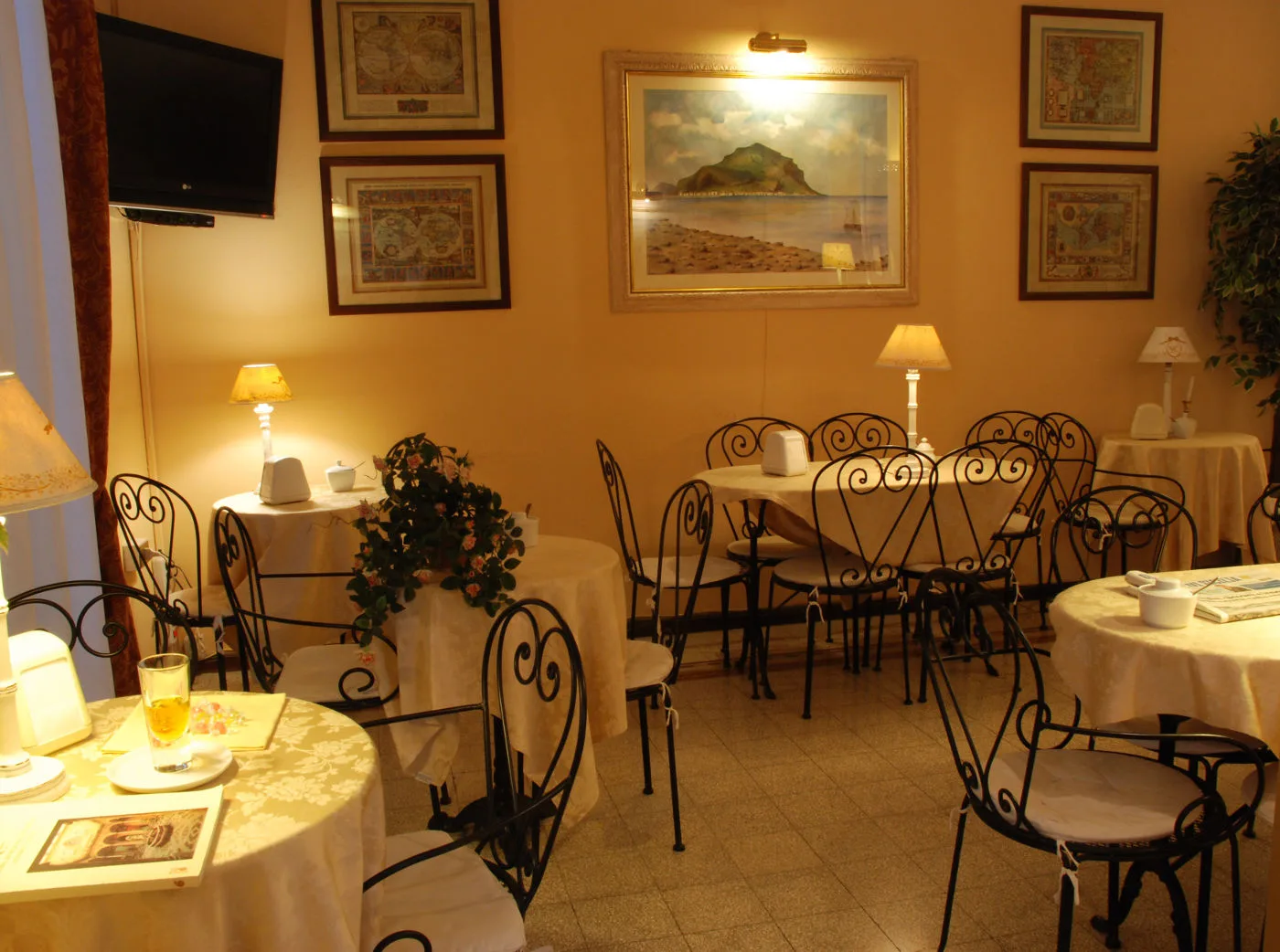 Representative hotel space: A warmly lit dining room with tables, metal seating, and framed artwork.