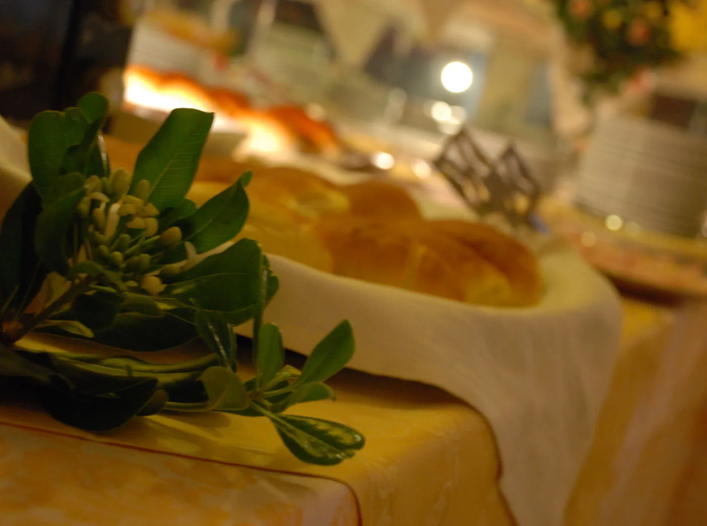 Representative hotel space: A warmly lit dining table displays a loaf of bread beside a leafy centerpiece.
