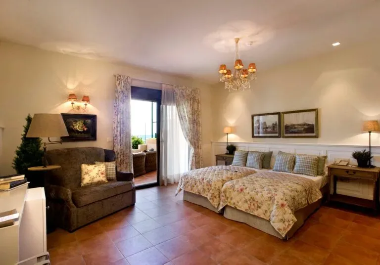 Representative hotel space: A bedroom with two beds, a seating area, and a glass door opening onto a balcony.