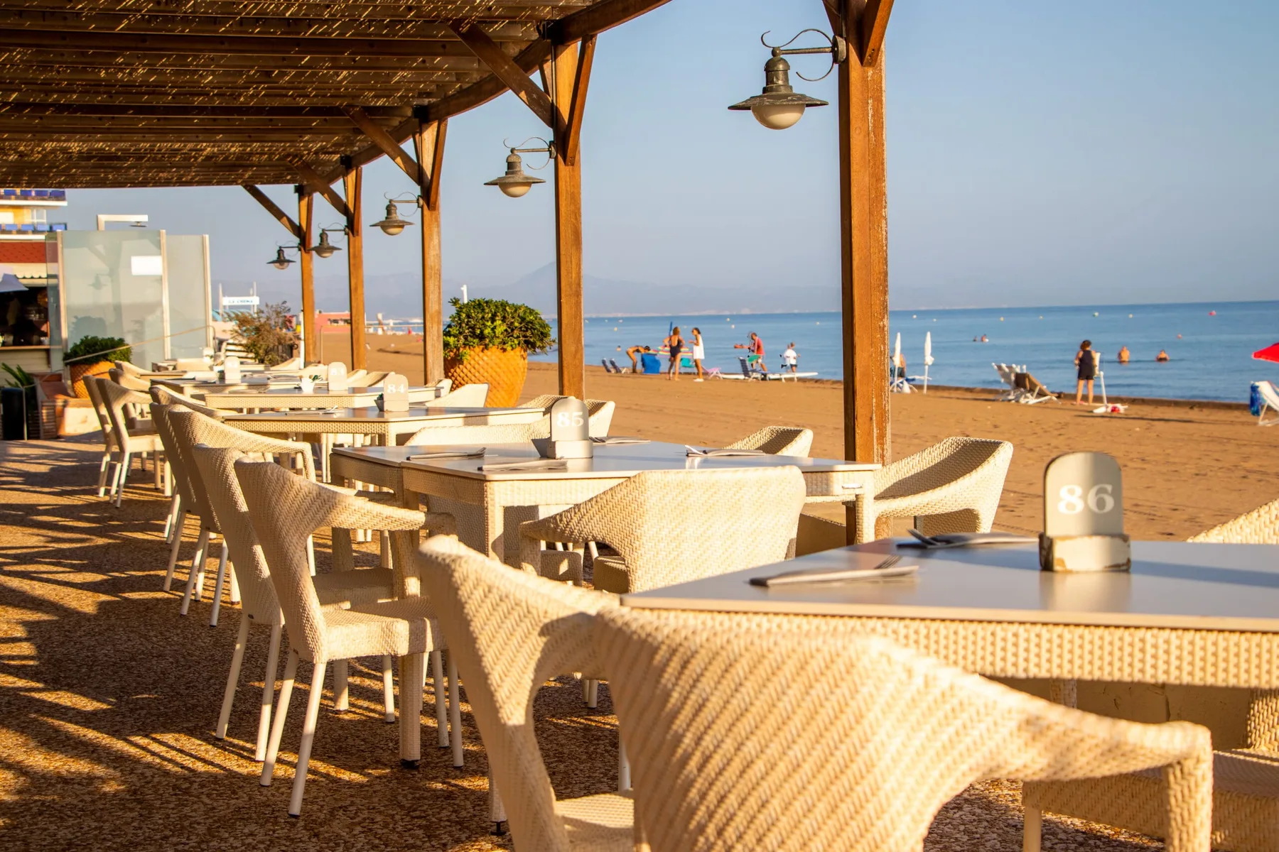 Representative hotel space: A covered beachfront dining area with tables and seating overlooking the sea.