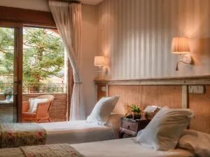 Representative hotel space: A bedroom with two beds, bedside lamps, and glass doors opening to a balcony.