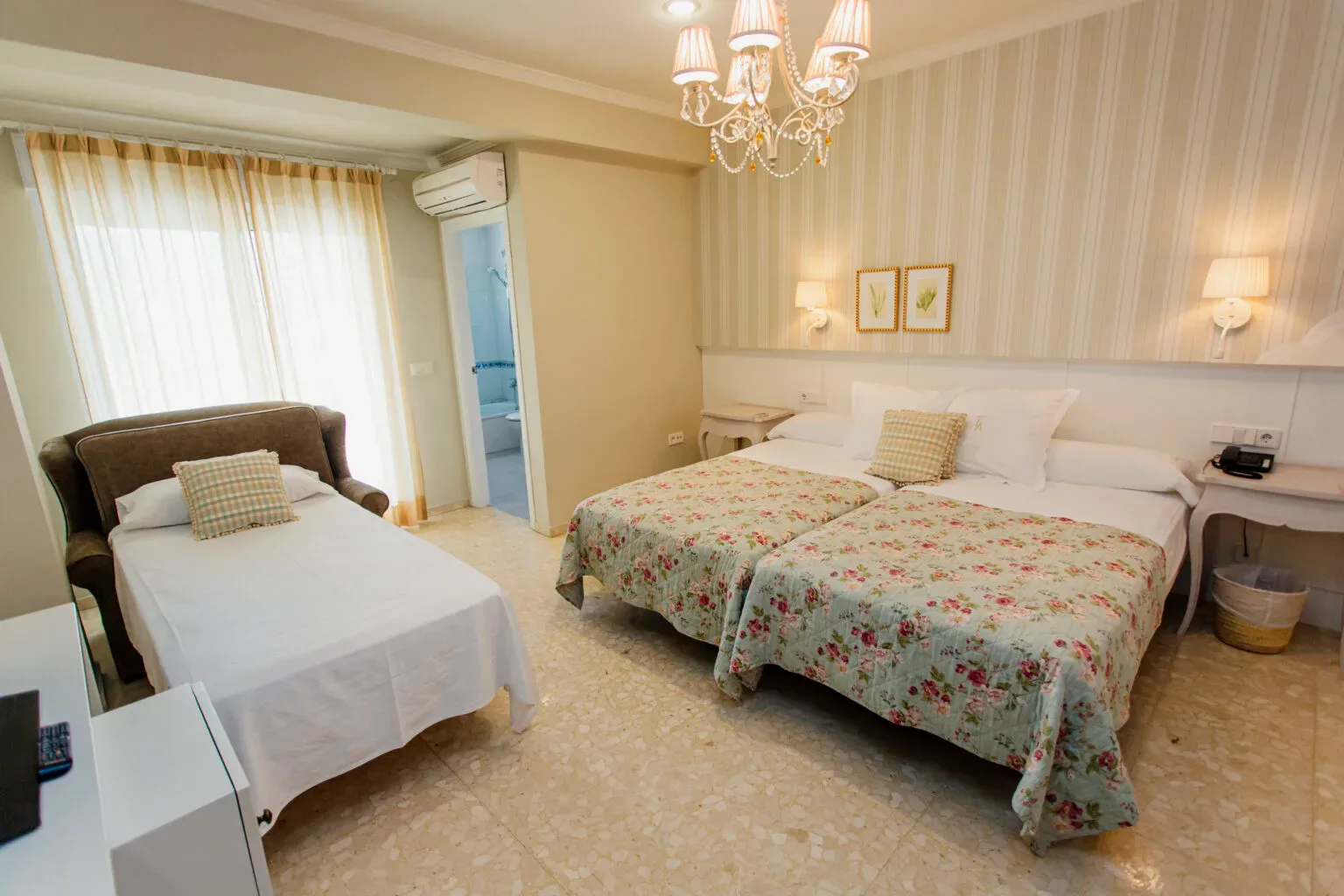 Representative hotel space: A bedroom with two beds, floral bedspreads, and a curtained window.