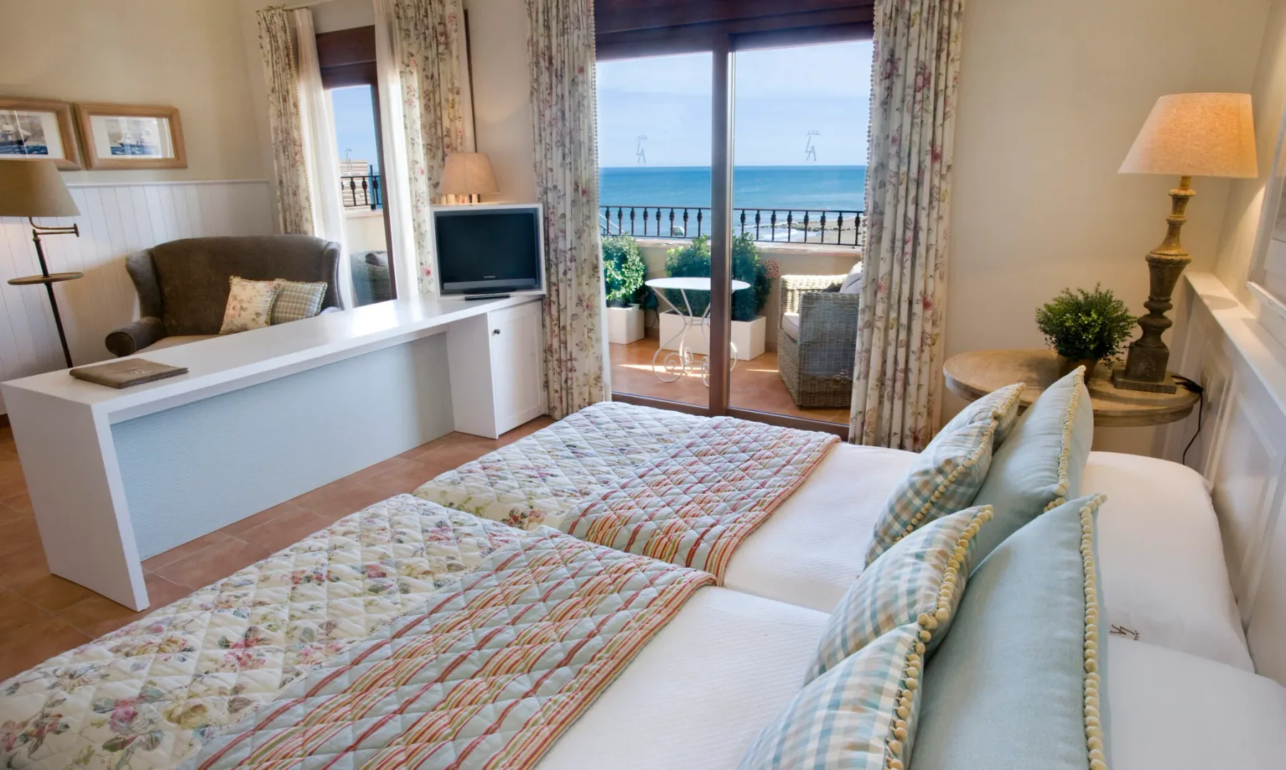 Representative hotel space: A bright bedroom with two beds and glass doors opening onto a sea view.