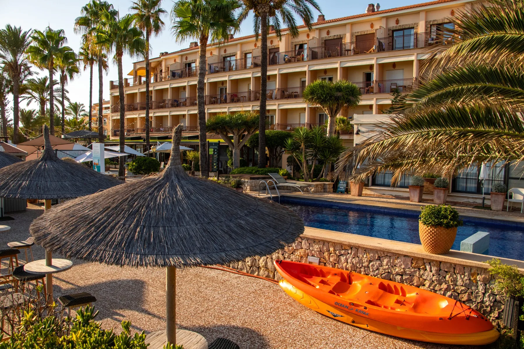 Representative hotel space: A hotel pool area with a bright orange kayak and palm trees.