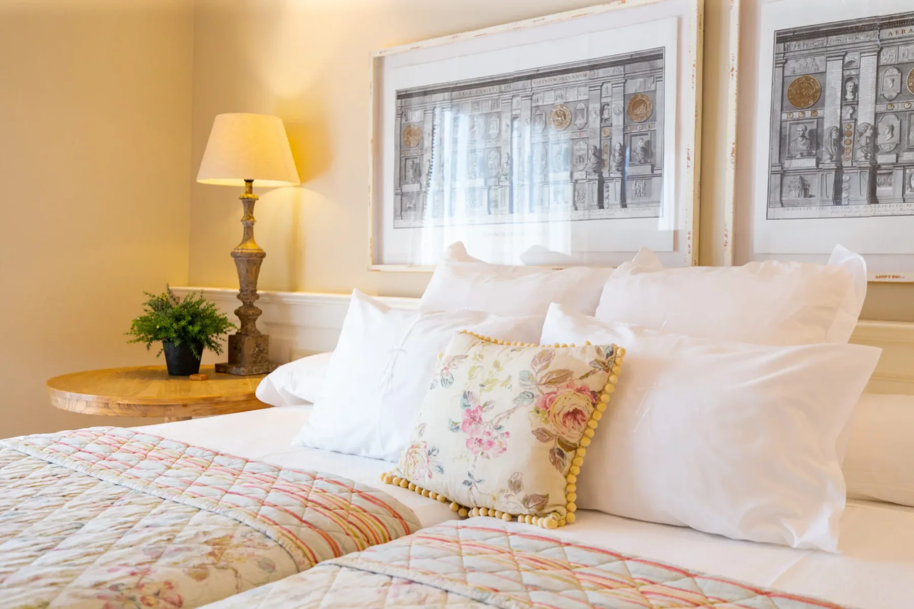 Representative hotel space: A bedroom with two beds, floral pillows, and framed artwork above the headboard.