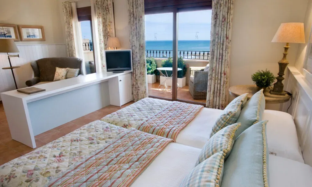 Representative hotel space: A bedroom seating area opens onto a balcony overlooking the sea.