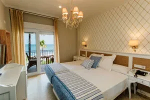 Representative hotel space: A hotel bedroom with a large bed, bedside tables, and a balcony door.