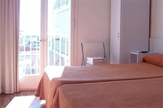 Espacio representativo del hotel: Un dormitorio con una cama junto a puertas de vidrio luminosas que dan a un balcón.