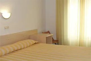 Espacio representativo del hotel: Un dormitorio con una cama junto a una ventana con cortinas.