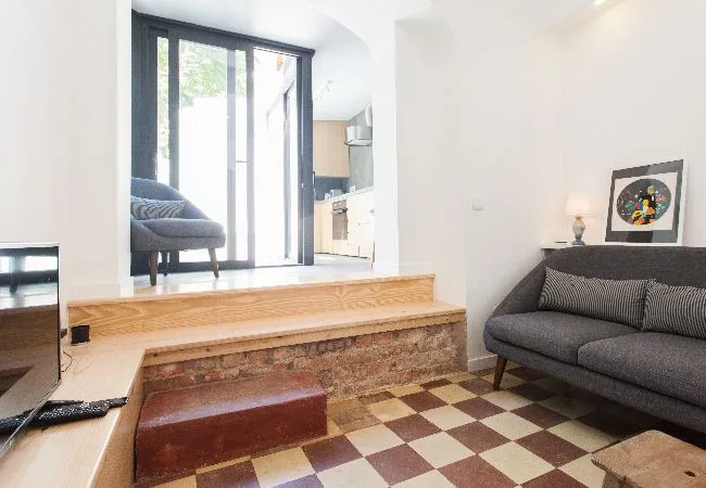 A bright living room with seating beside a raised area and large glass doors.