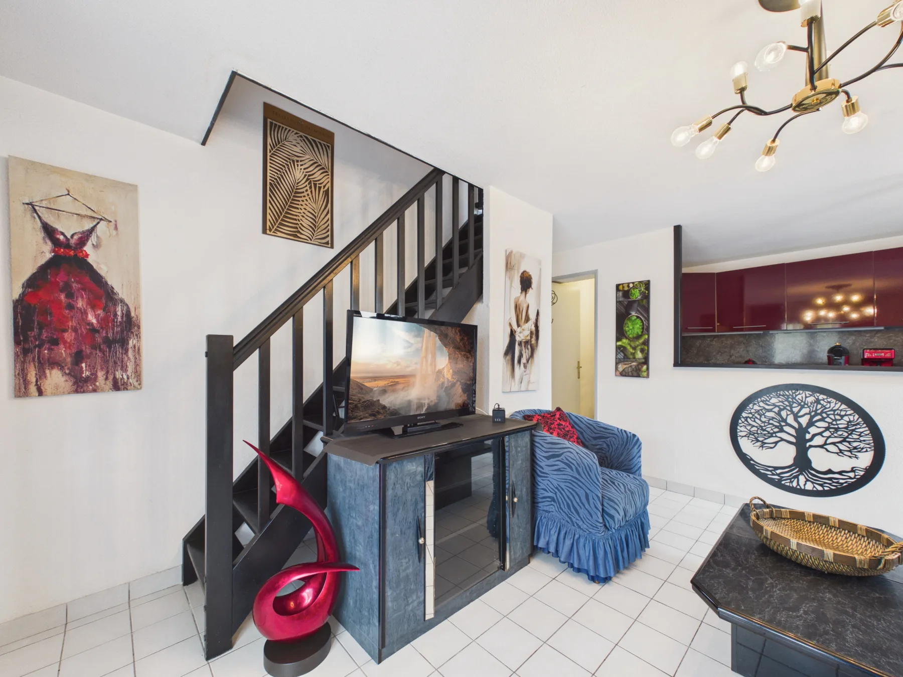 A living area with a television beside a staircase and blue seating.