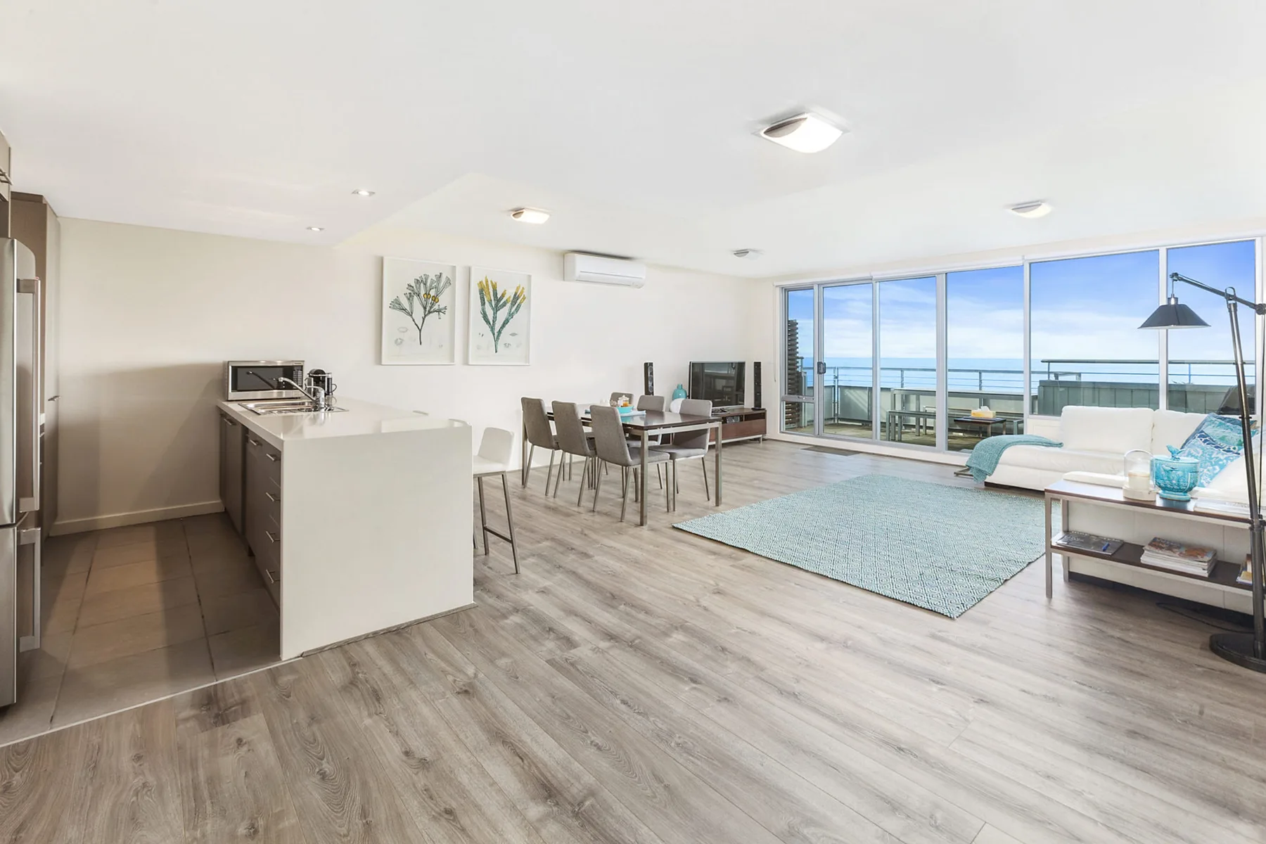 An open-plan living and dining area with a kitchen counter and ocean views.