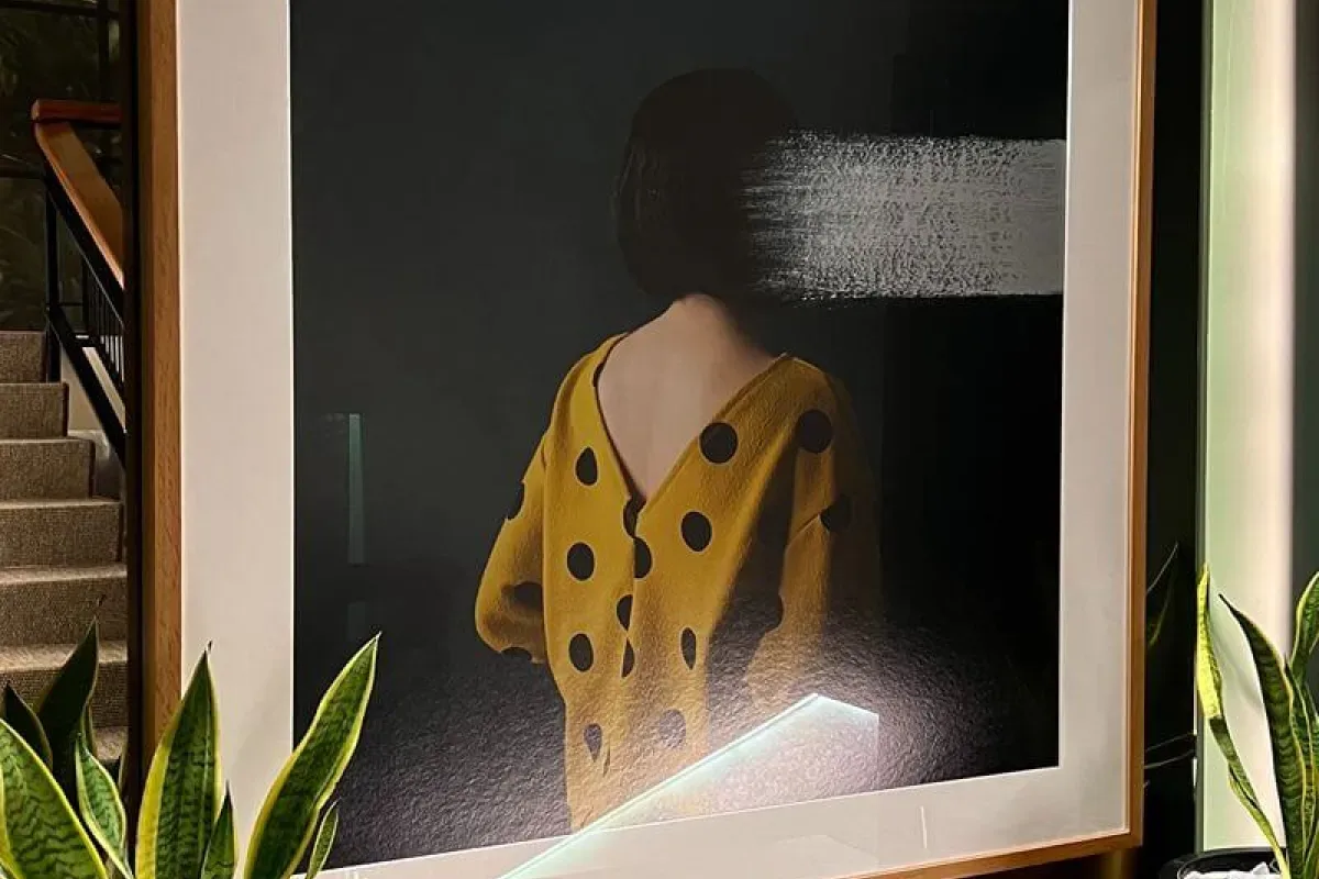 Representative hotel space: A framed photograph of a person in a yellow polka-dot outfit hangs above leafy plants.