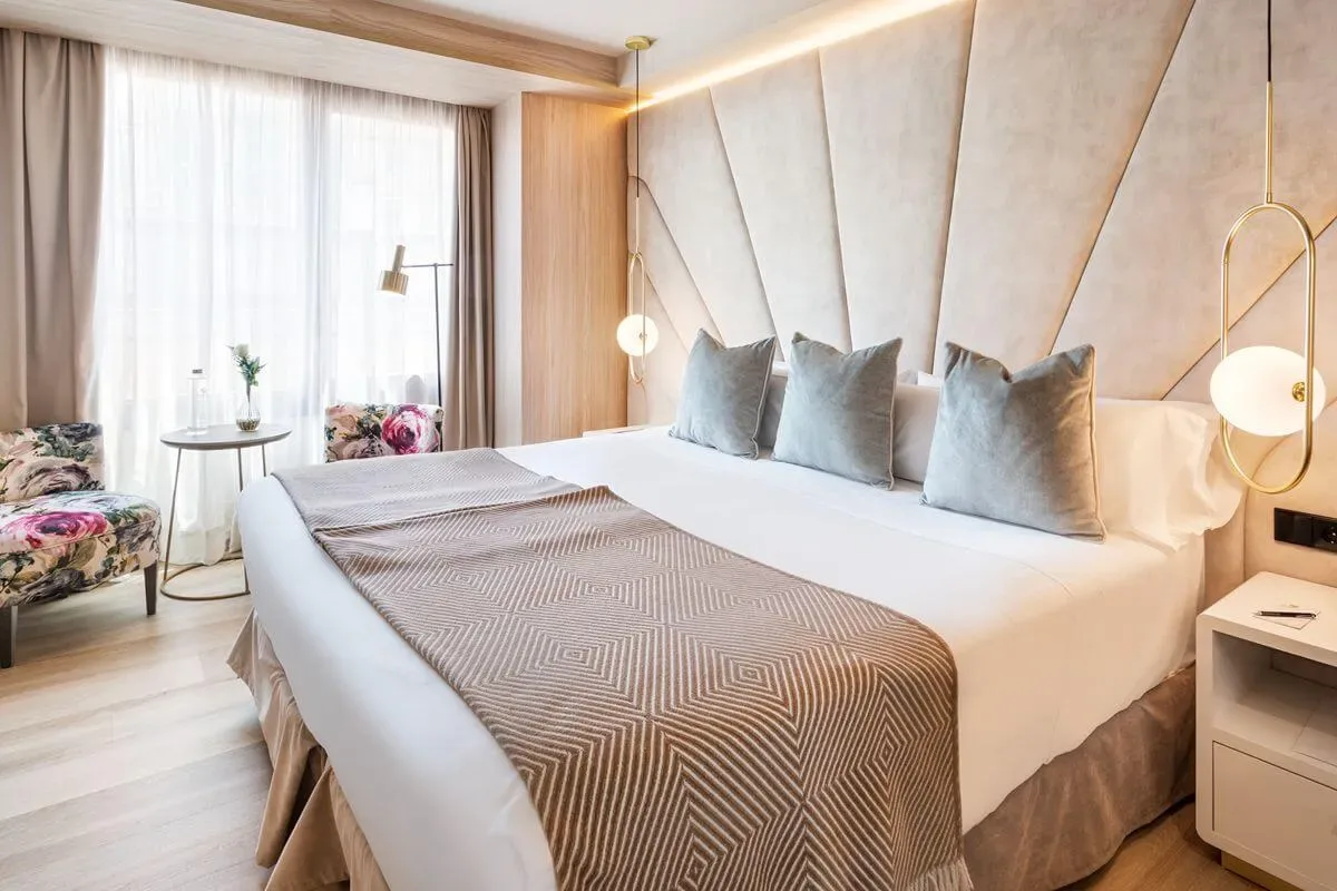 Representative hotel space: A bedroom with a neatly made bed and upholstered headboard.