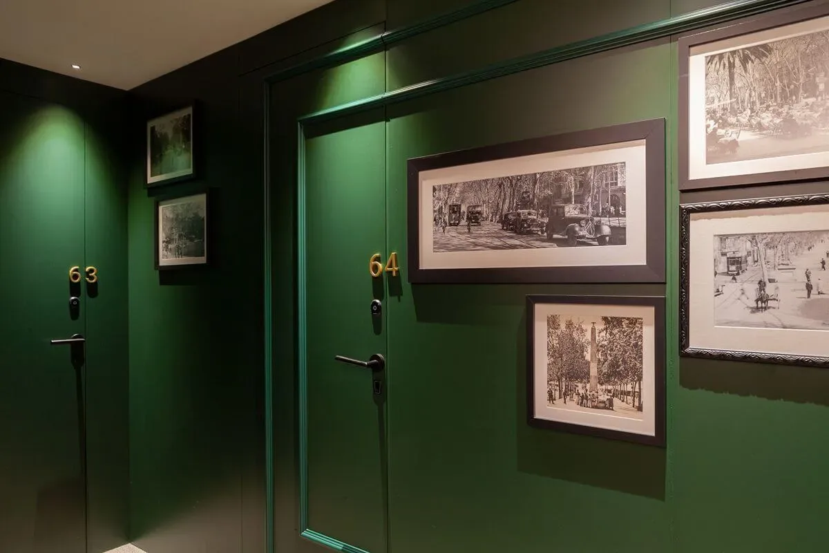 Representative hotel space: A dark green hotel hallway with numbered doors and framed photographs.