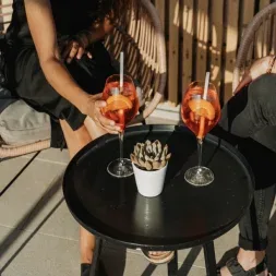 Representative hotel space: A small round table with two drinks and a potted plant sits between seated people.