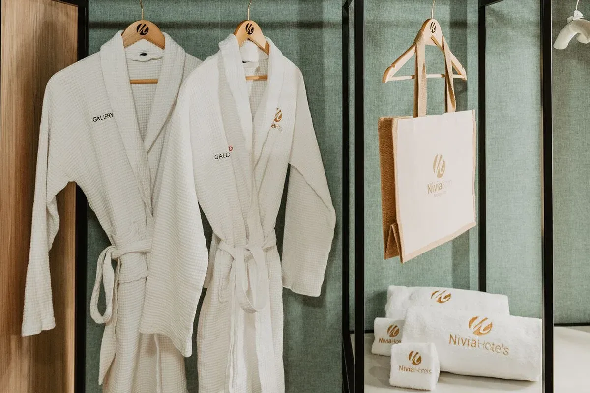 Representative hotel space: Two white robes hang beside branded towels and a tote bag.