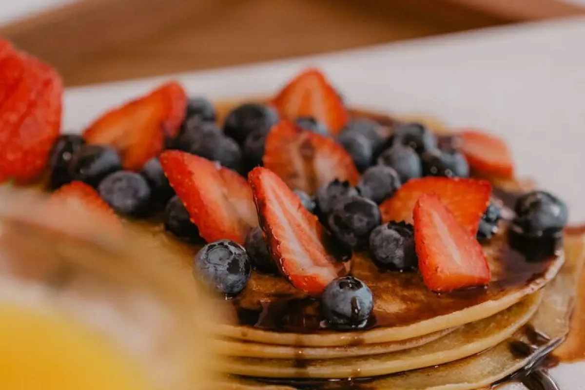 Representative hotel space: A stack of pancakes topped with strawberries and blueberries.