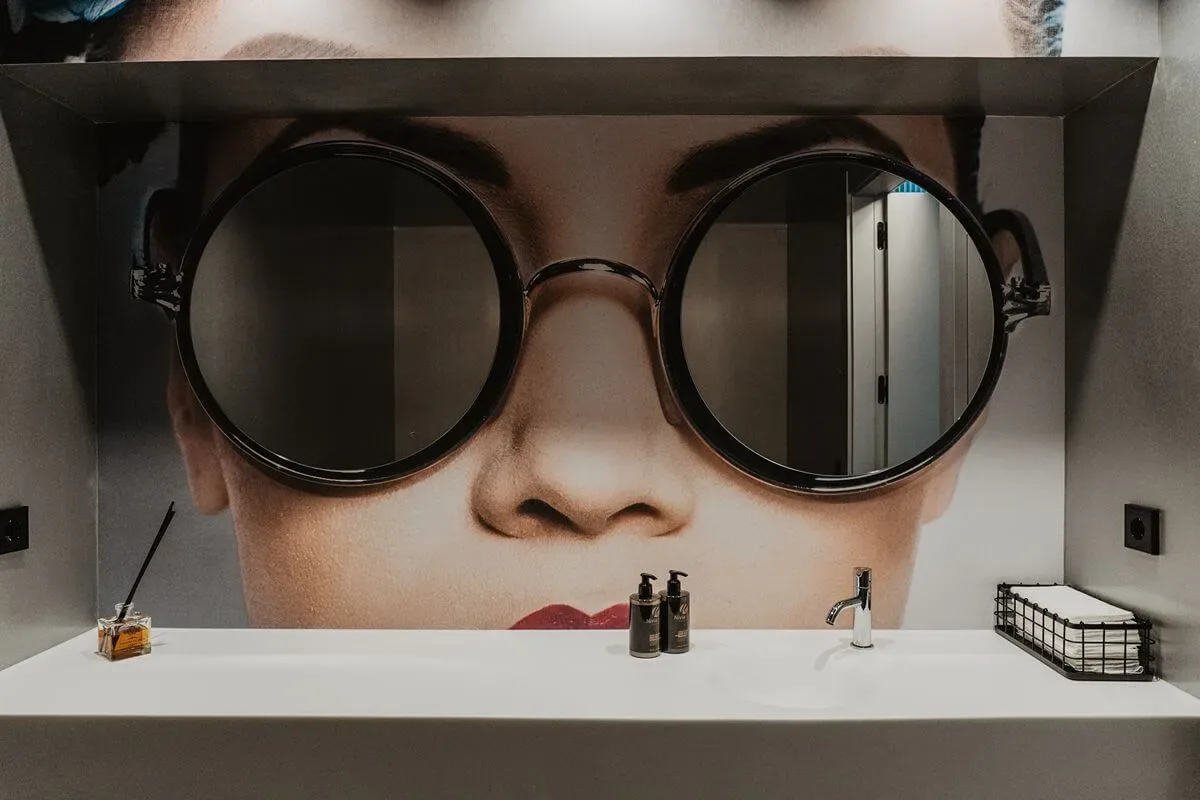 Representative hotel space: A bathroom vanity sits beneath a large mural of a face wearing round glasses.