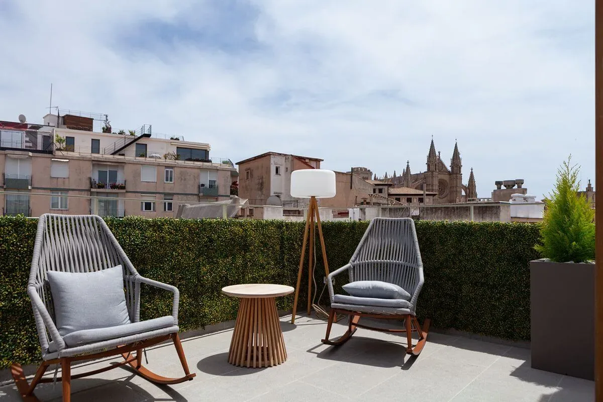 Representative hotel space: A rooftop terrace has two outdoor seats and a small table beside a hedge.