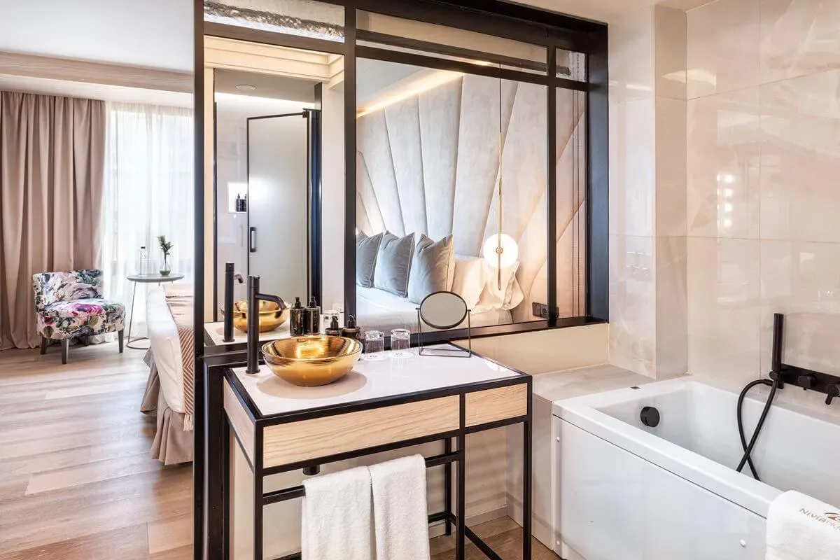 Representative hotel space: A bedroom and bathroom share an open view, with a bathtub beside the vanity.