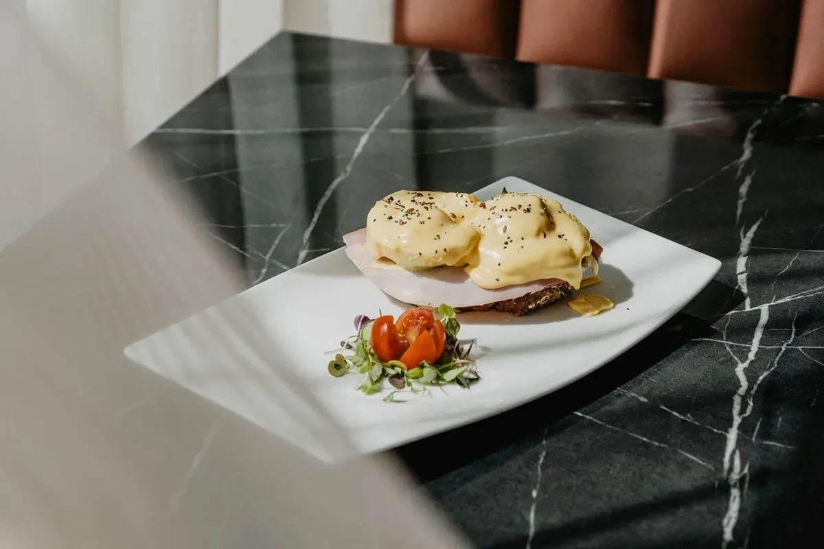 Representative hotel space: A plated breakfast dish with sauce and tomato garnish rests on a dark countertop.