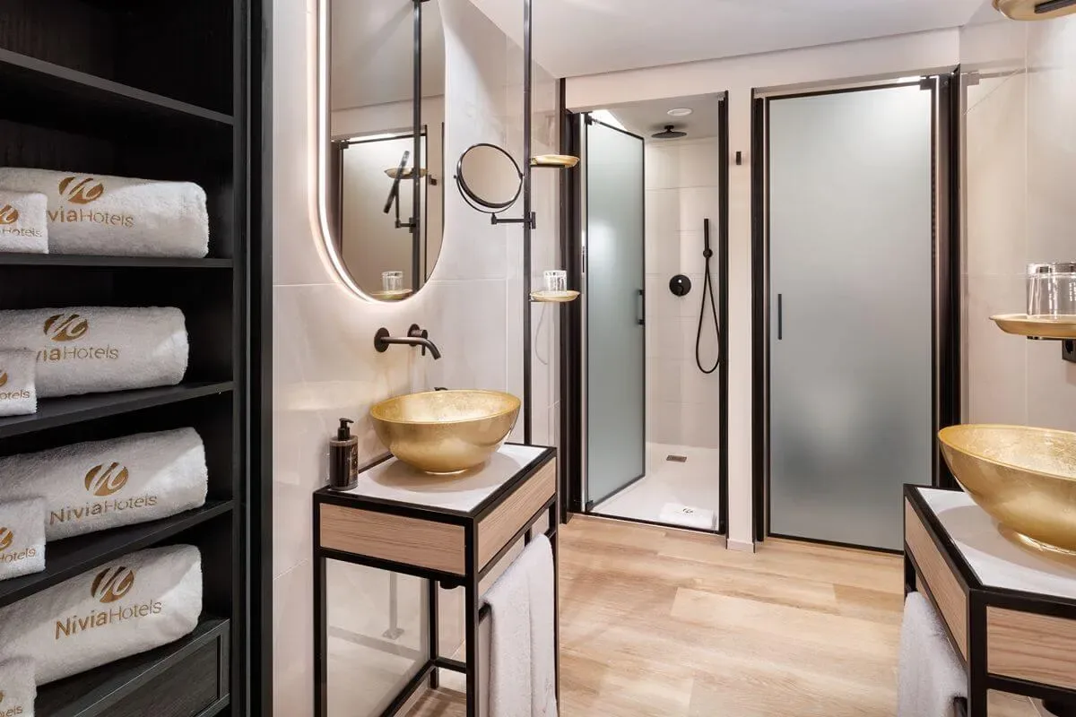 Representative hotel space: A modern bathroom with a glass shower and two sink areas.