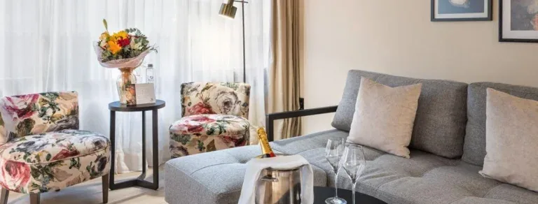 Representative hotel space: A living room with a gray sofa and floral armchairs.