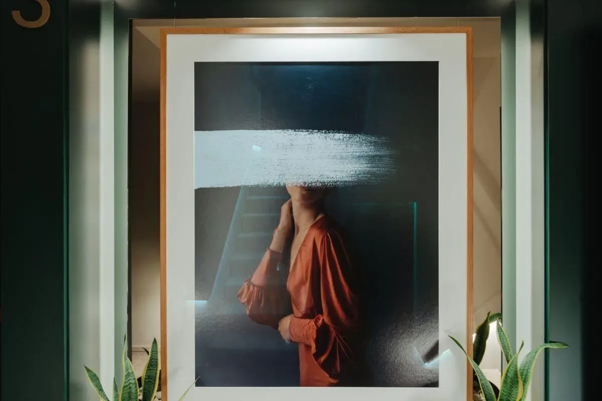 Representative hotel space: Framed portrait artwork hangs on a dark wall between green plants.