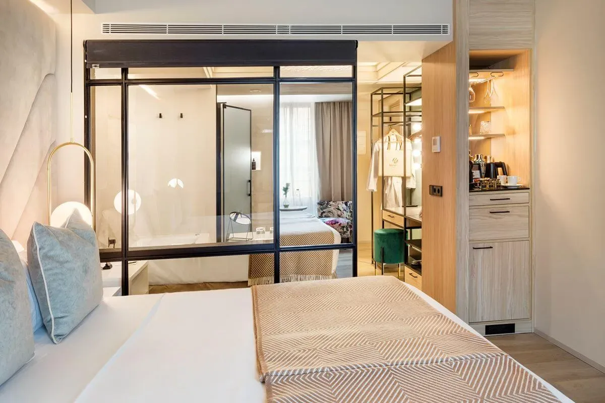 Representative hotel space: Bedroom with a bed beside a glass partition and a built-in storage area.