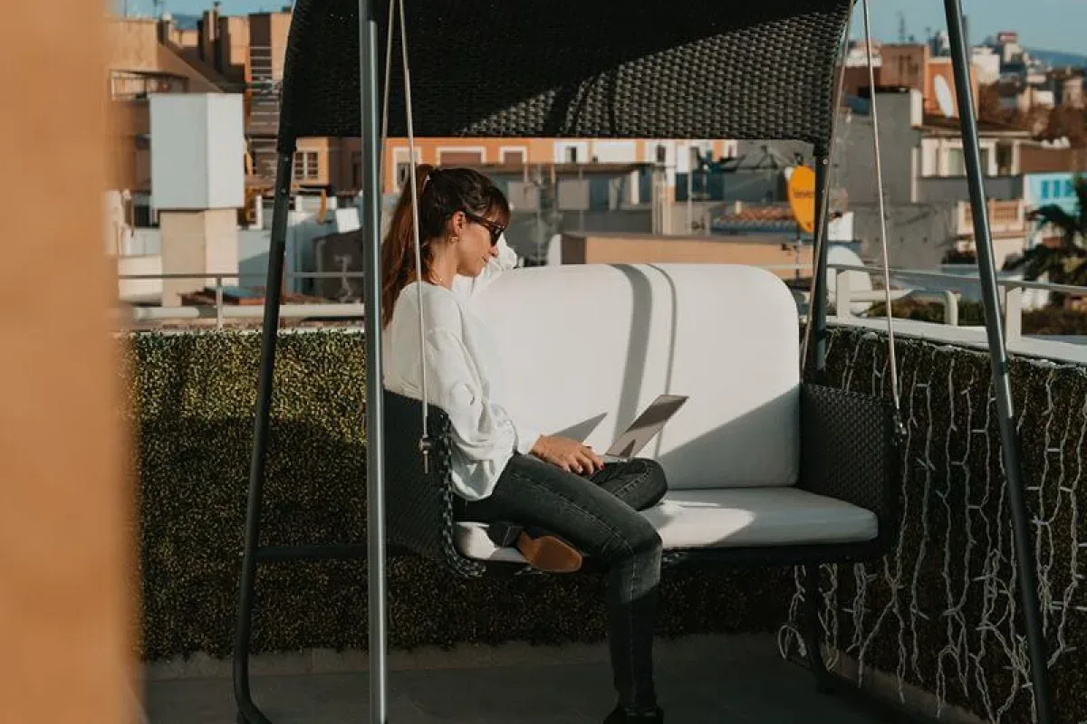 Representative hotel space: A person sits on an outdoor cushioned seat beneath a dark canopy.