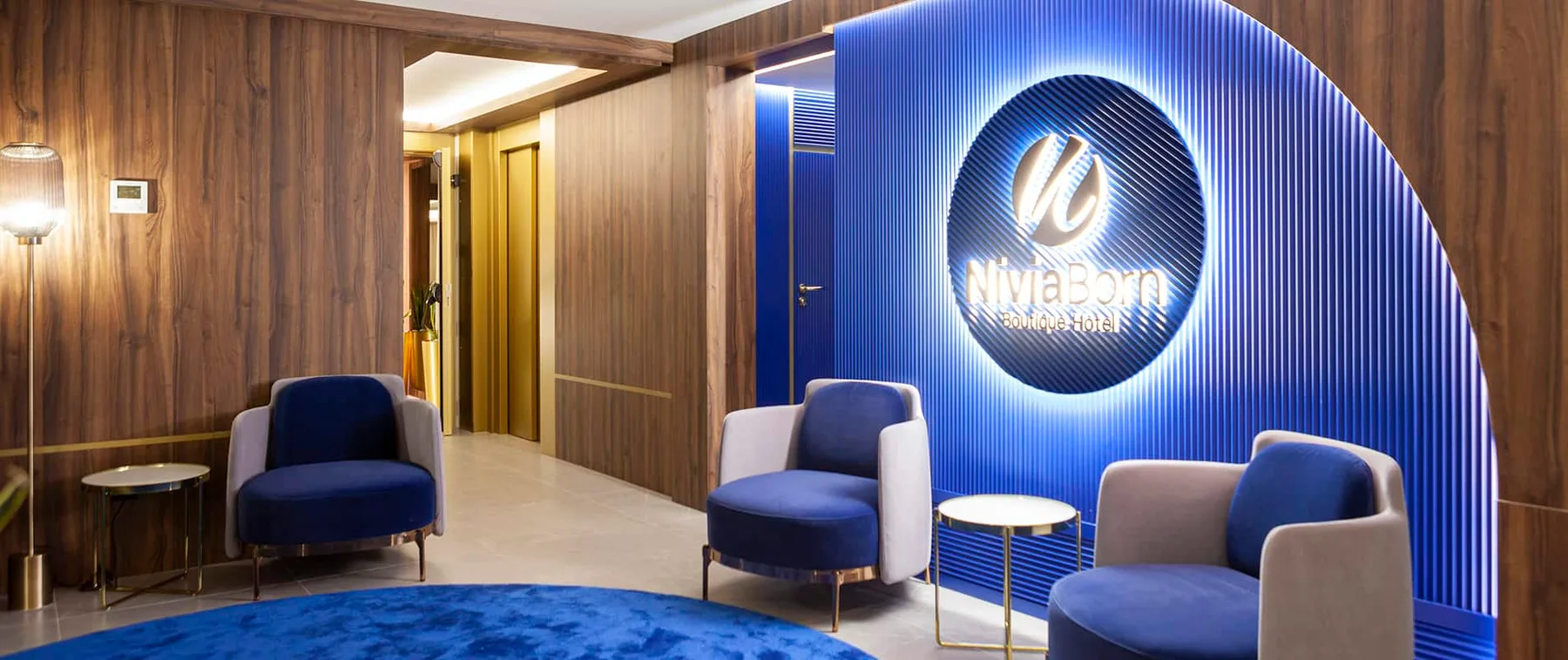 Representative hotel space: A hotel lobby seating area with blue chairs beside an illuminated wall sign.