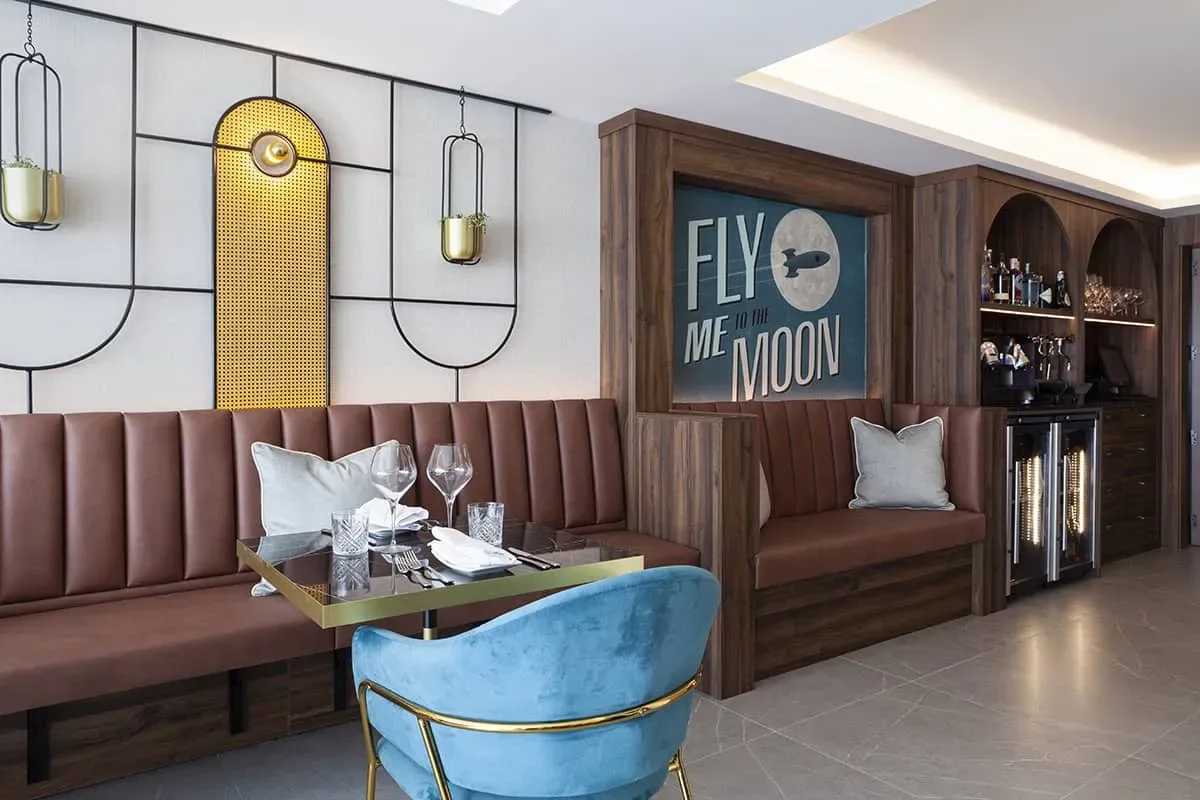 Representative hotel space: A restaurant dining area has booth seating, a table, and a blue chair.