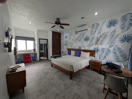 Representative hotel space: A bedroom with a bed, patterned wallpaper, and a ceiling fan.