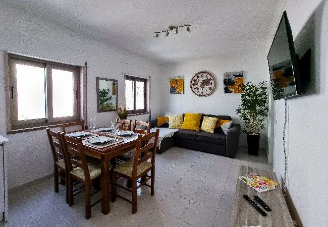 A living and dining room with a wooden dining table and dark seating.
