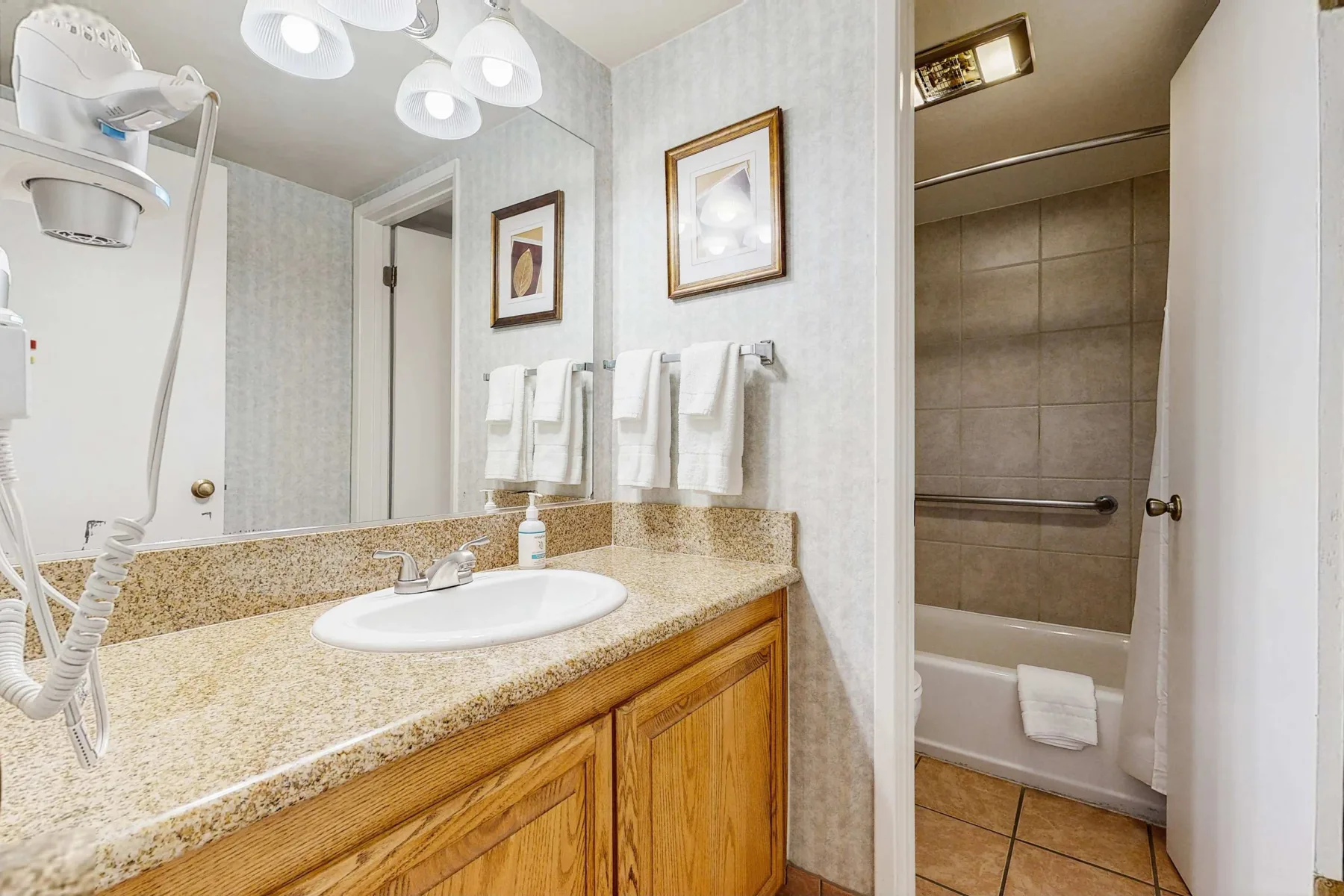 A bathroom vanity with a sink and mirror beside a bathtub.