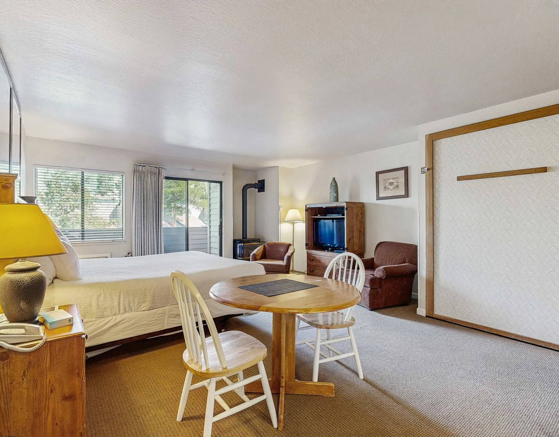 A bedroom and sitting area share an open space with a round dining table.