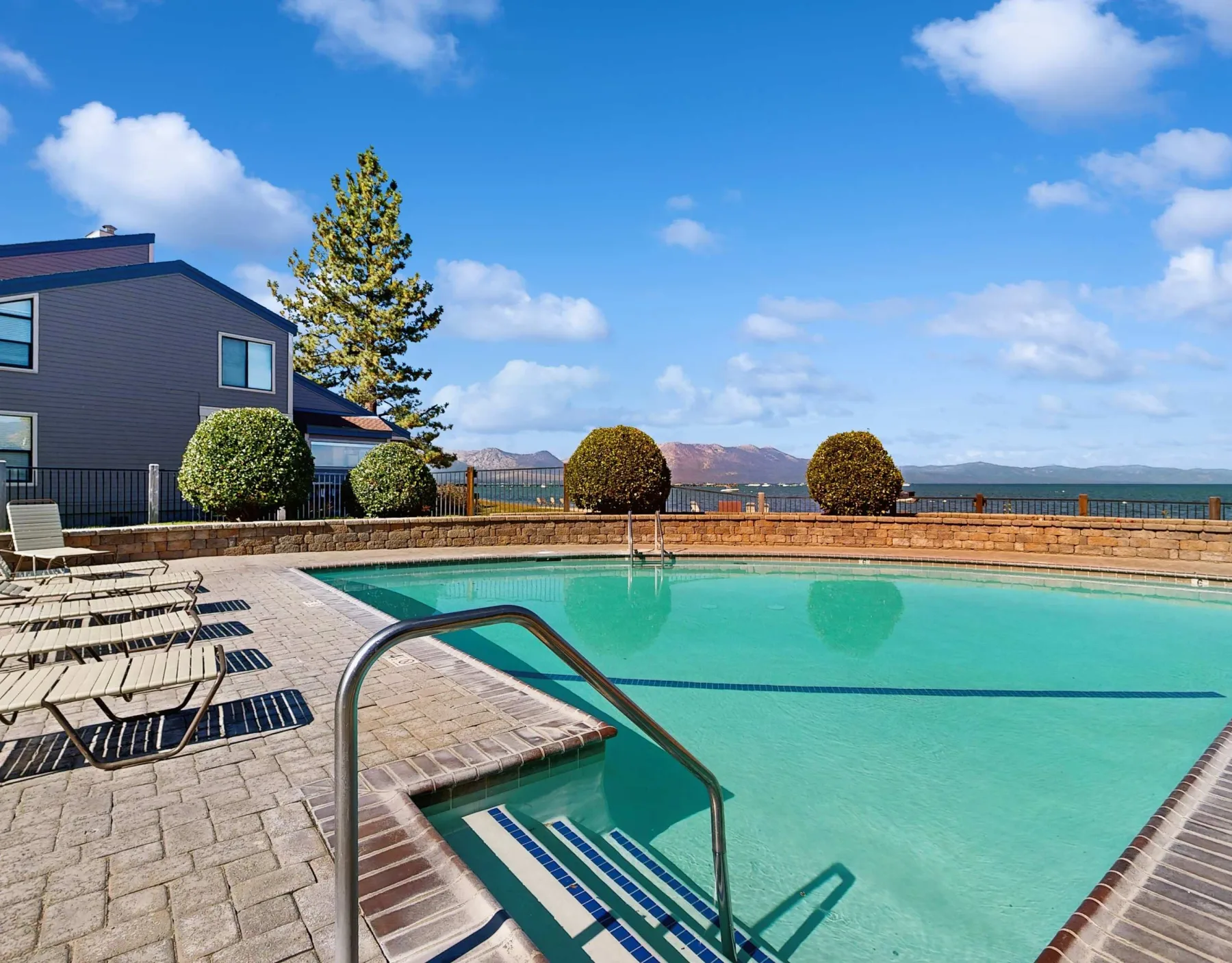 Shared amenity: Outdoor swimming pool beside a paved deck with seating and a distant mountain view.
