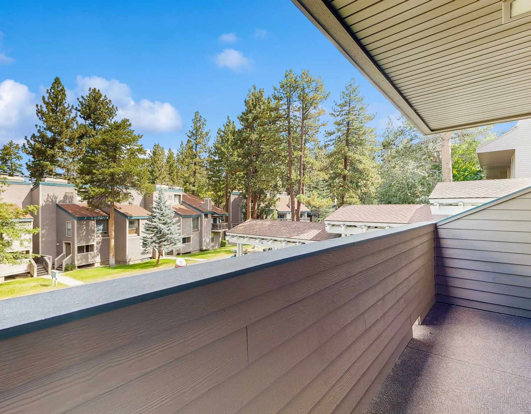 A balcony overlooks nearby buildings and a tree-filled landscape.