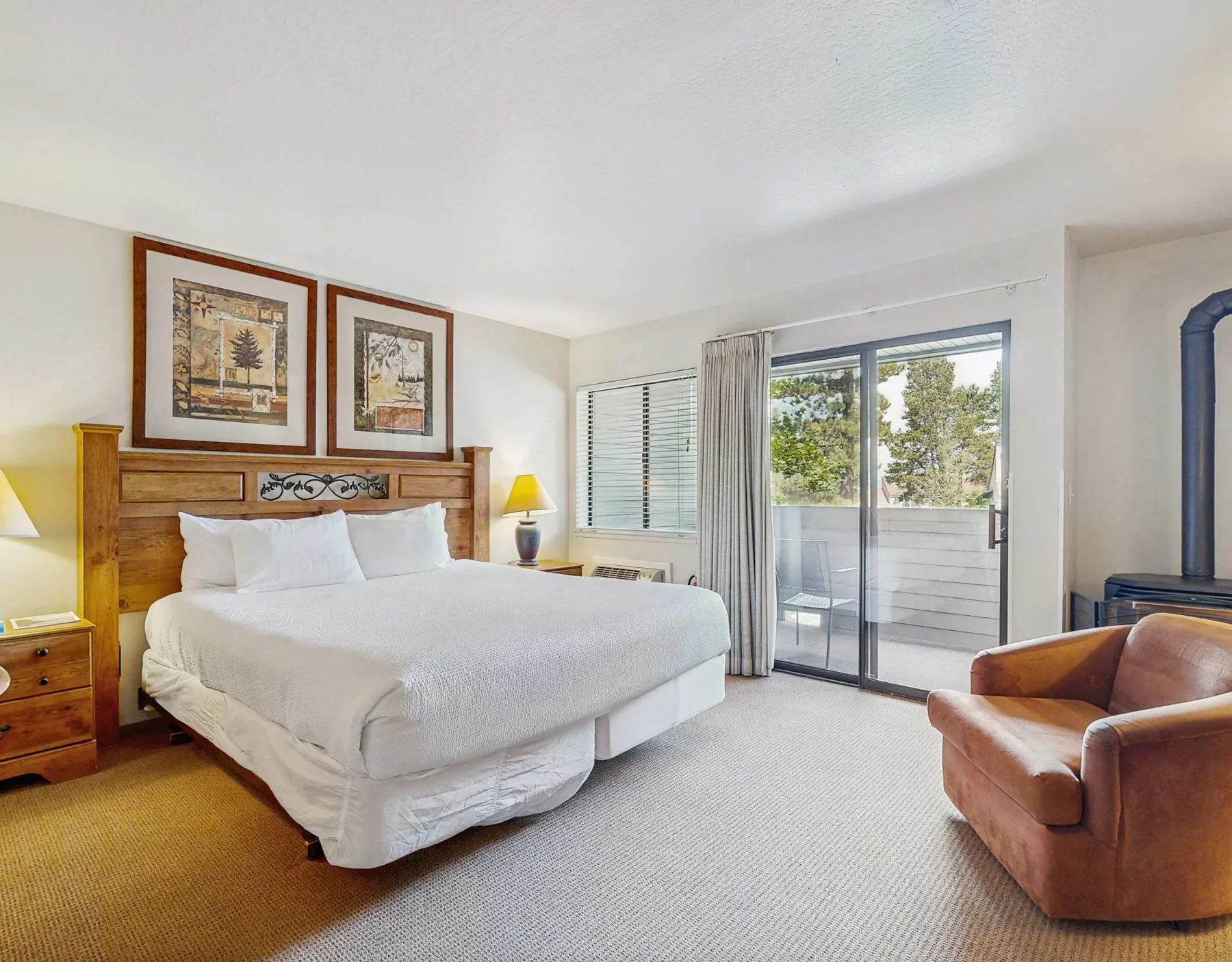 Bedroom with a bed, bedside lamps, and sliding glass doors opening onto a balcony.
