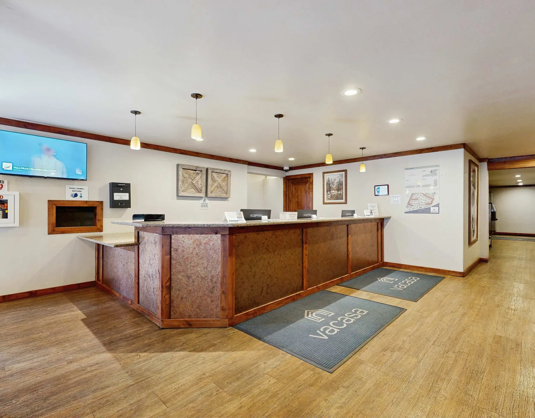 Shared amenity: A reception counter with floor mats and wall displays in a lobby.