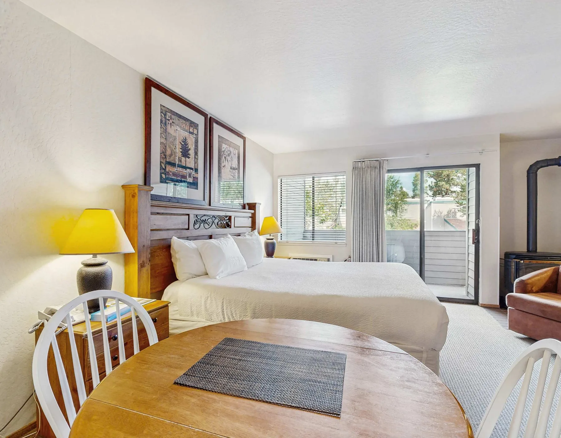 A bedroom with a bed, bedside lamps, and a sliding glass door.