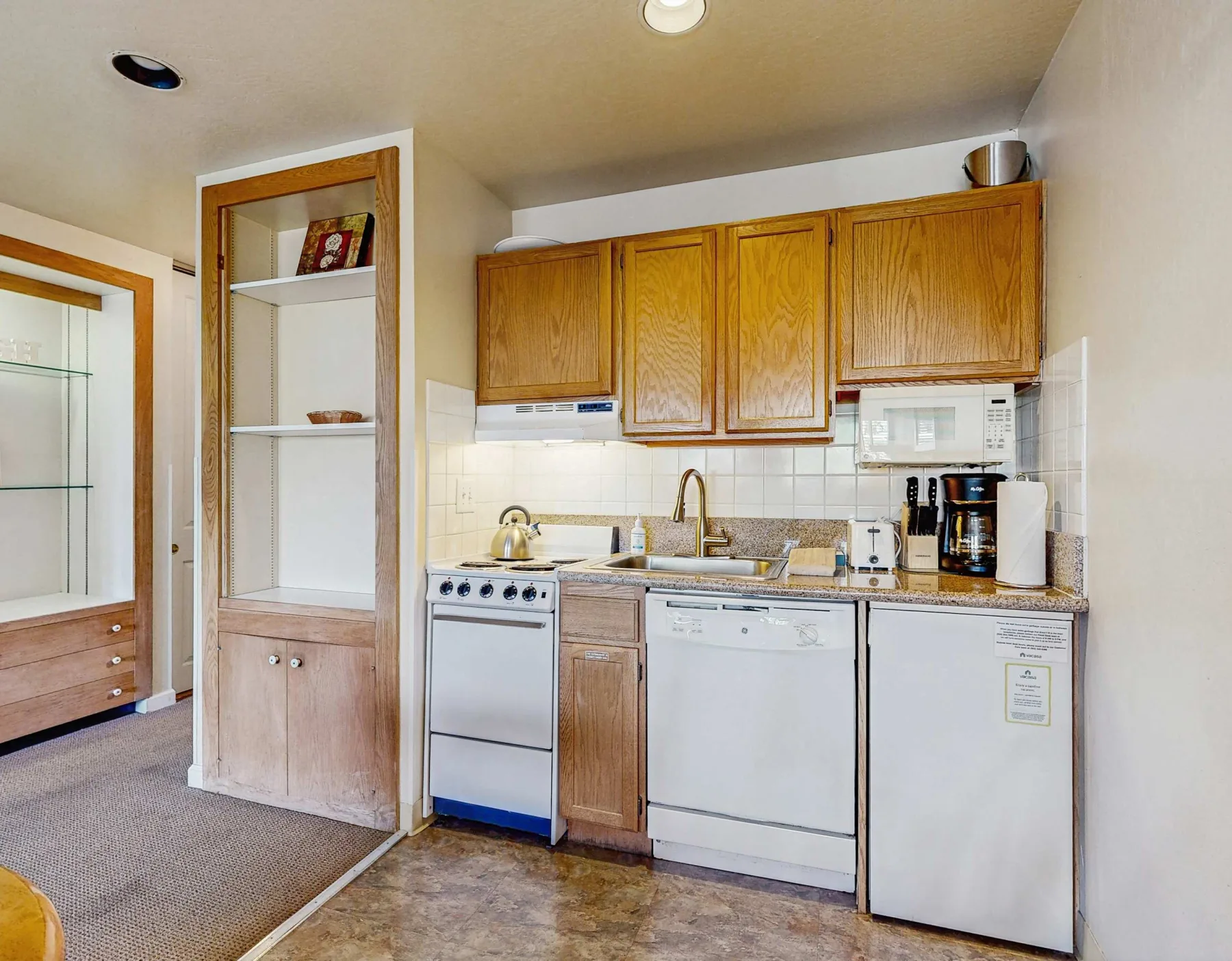 A compact kitchen with wooden cabinets, a sink, and kitchen appliances.