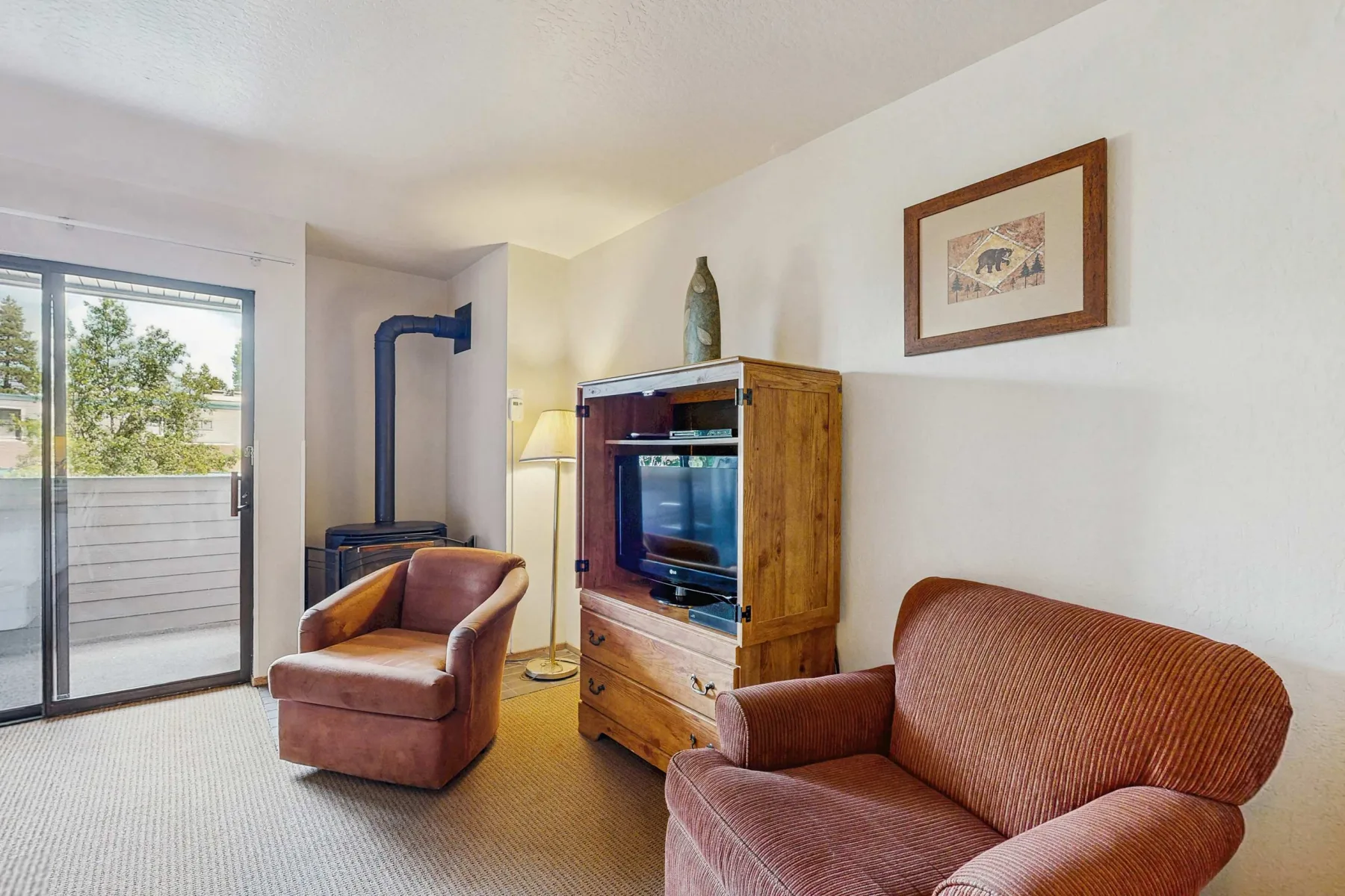 A living room with seating, a television cabinet, and a sliding glass door.