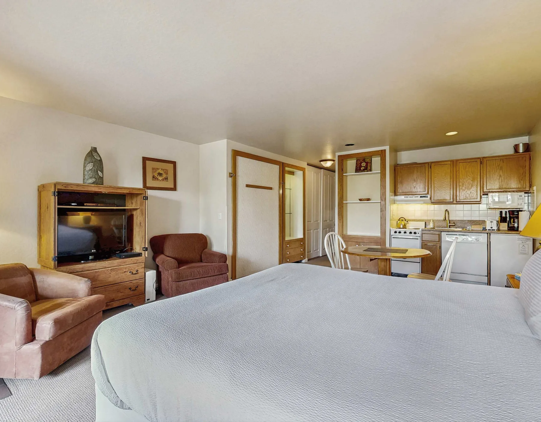 A studio room with a bed, seating area, and kitchenette in the background.
