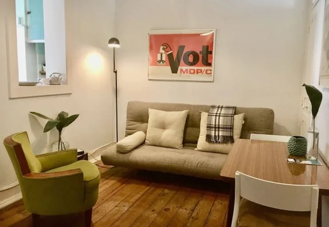 Una sala de estar con asientos, una lámpara de pie y suelo de madera.