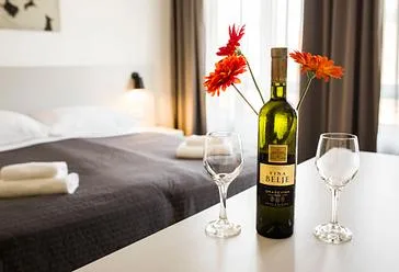Representative hotel space: A bedroom with a bed, flowers, and wine glasses on a table.