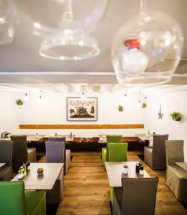 Representative hotel space: A restaurant dining room has rows of tables and chairs beneath hanging glass lights.