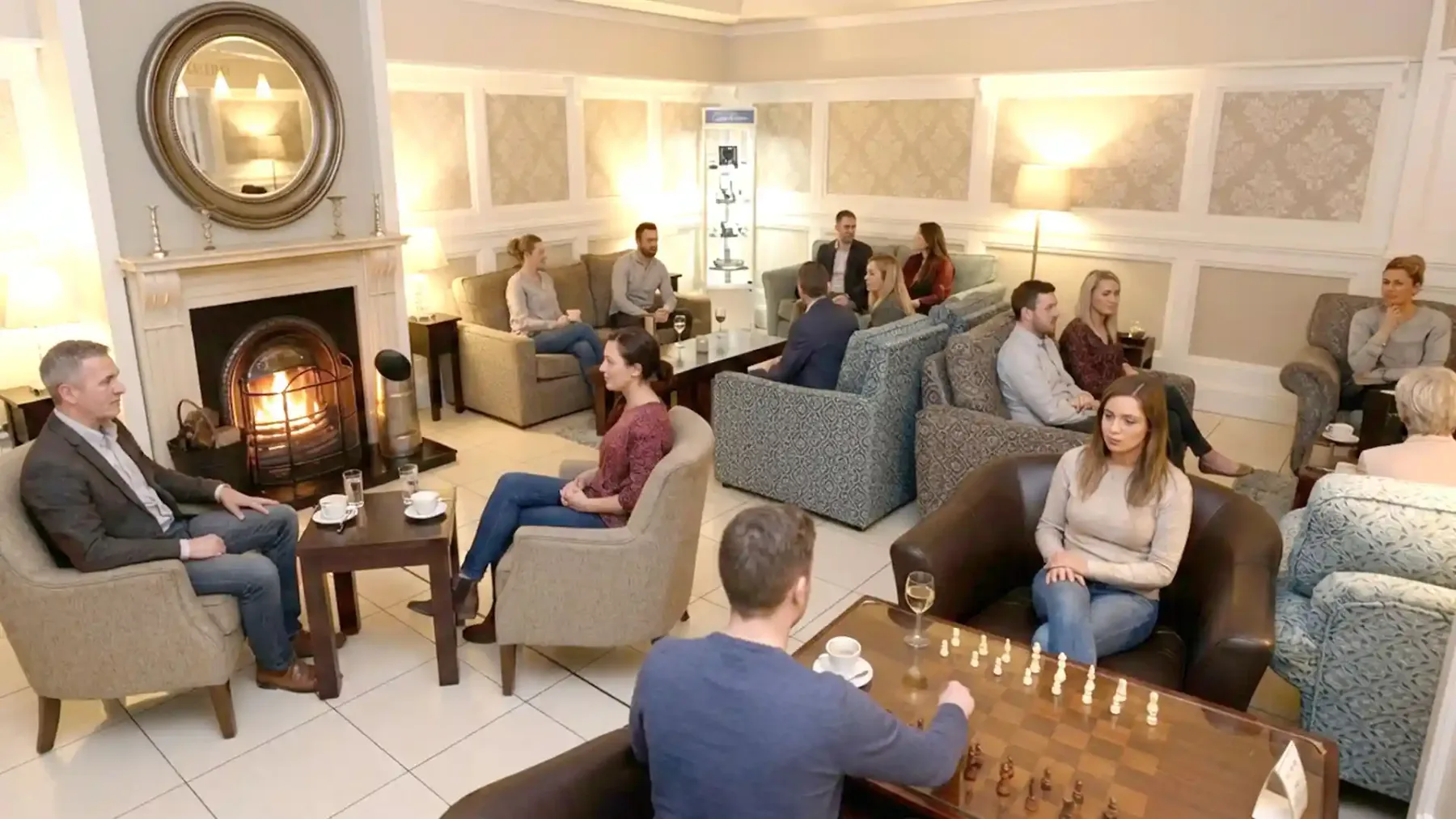 Representative hotel space: A lounge with guests seated around a fireplace and a chess table.